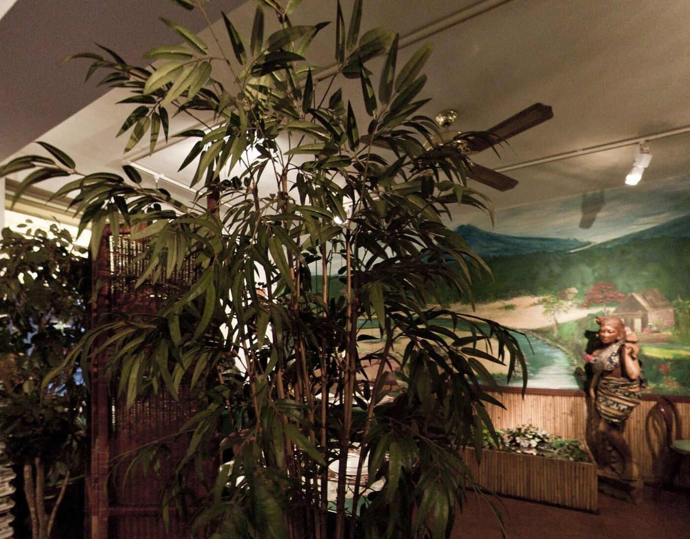 Eetzaal met bamboe en een grote muurschildering van een Indonesisch landschap